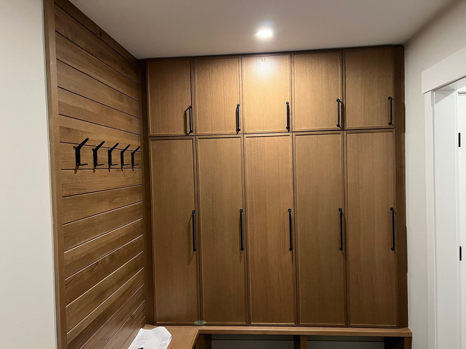 Floor to ceiling wood cabinetry set against a slatted accent wall