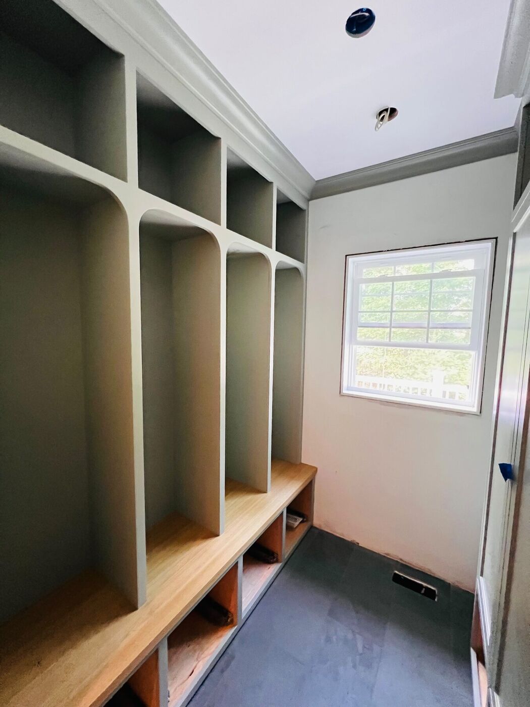 Green mudroom with built-in cubbies, bench, coat hooks and painted trim