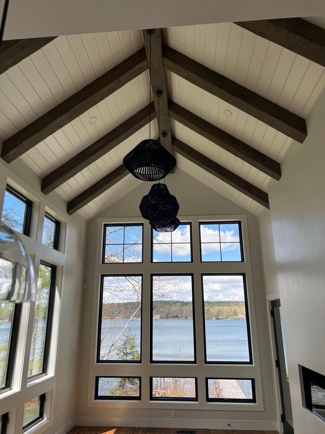 Vaulted ceiling with exposed beams above a wall of custom trimmed windows