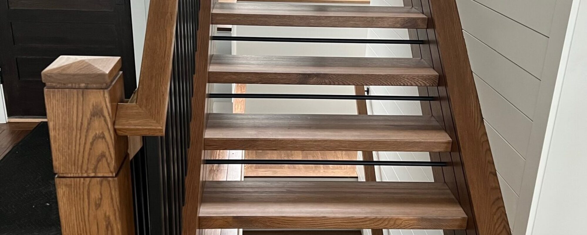 Staircase with a wood handrail, oak treads and slim metal balusters